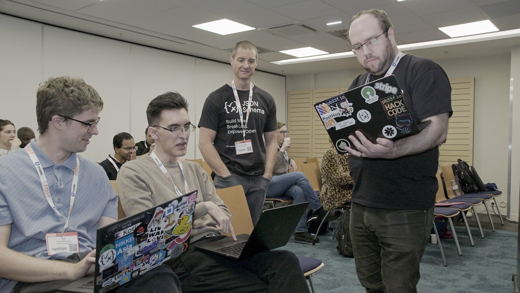 Four people are in this picture, three of them are with their computer and looking at it while the other member is looking at the computer in front of him. Two of them is seated while the other two is standing. From left to right, their names are Ryan Lee, Juan Cruz Viotti, Jason Desrosiers and Ben Hutton.
